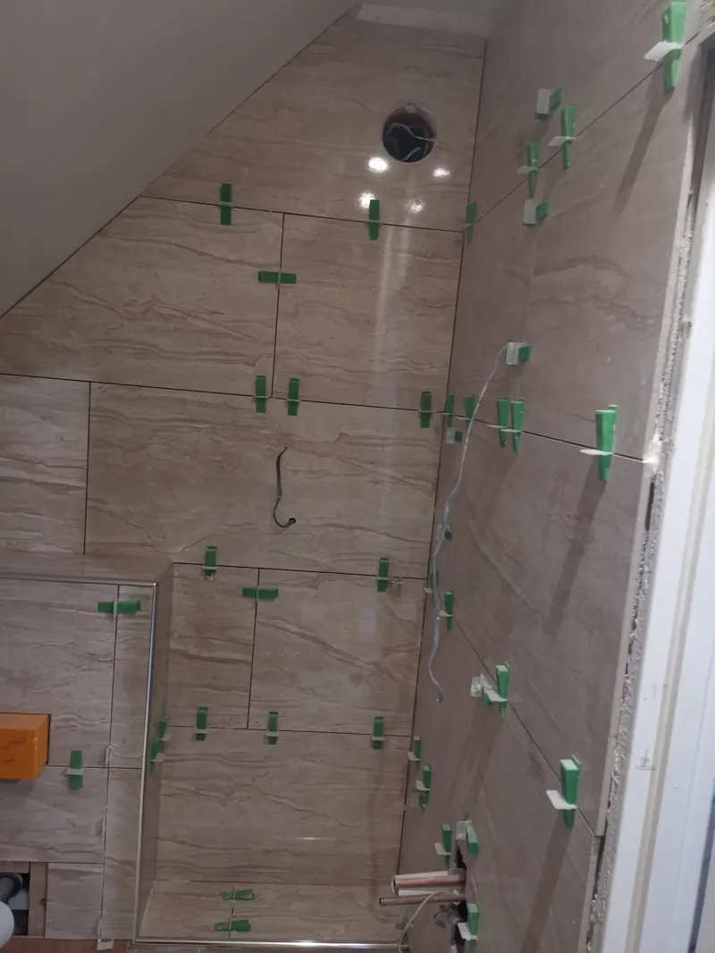 Tiled sloped ceiling in a loft shower area with a downlight fitted.