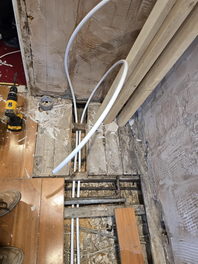 Plumbing pipes looped between floor joists ready for connection.